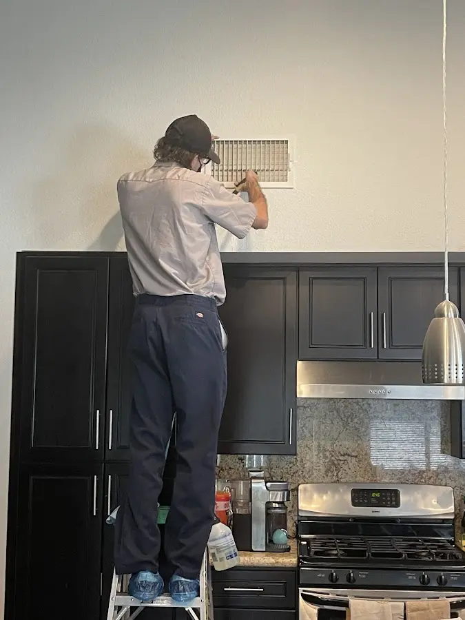 Technician inspecting an air vent during HVAC service in Richland